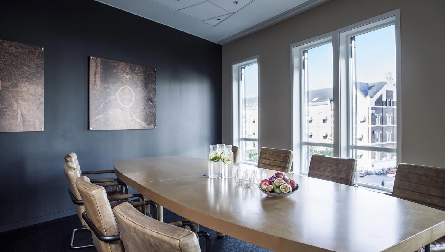 Meeting room with six chairs around the table. Apples and water pitchers on the table. Photo