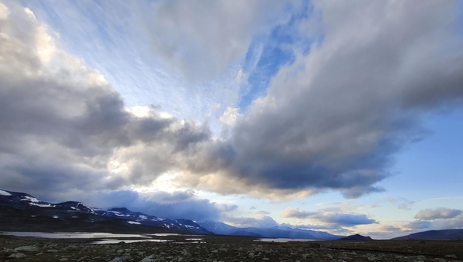 Fjellvidde med vann og høy himmel med masse kule skyer