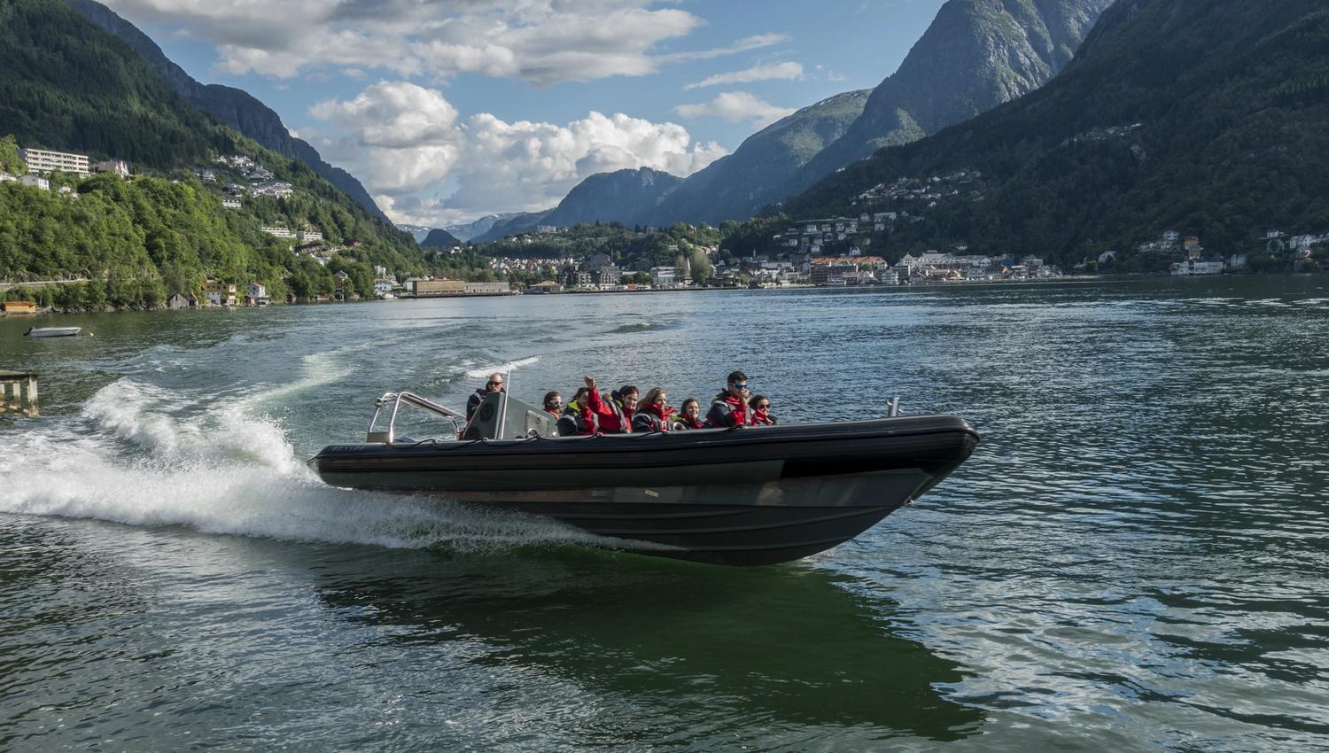A RIB boat speeds across the Hardangerfjord, surrounded by stunning mountains.