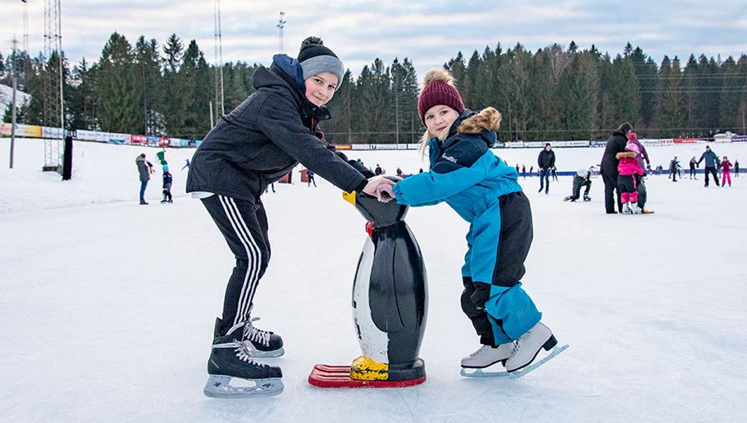 barn på skøyteisen, to som holder på en liten pigvin