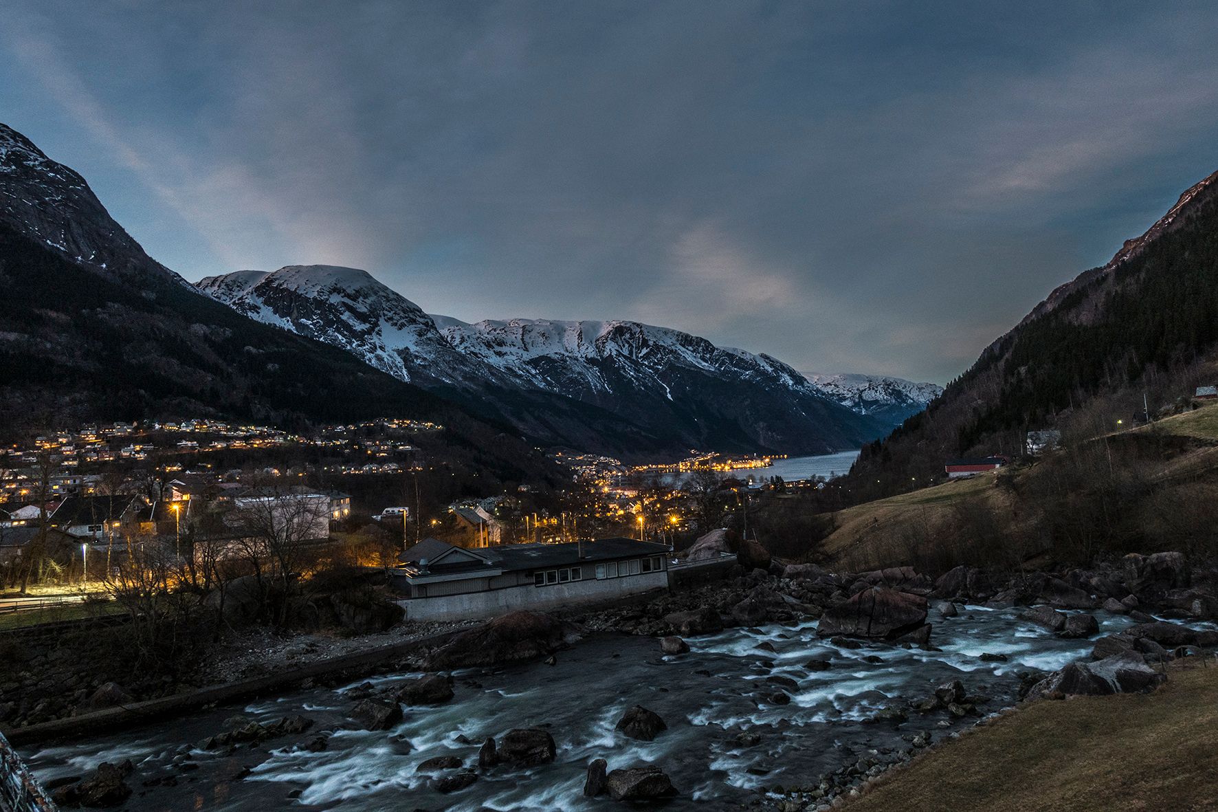 Spektakulær kveldsscene med fjord, elv og fjell opplyst av dei siste solstrålene.