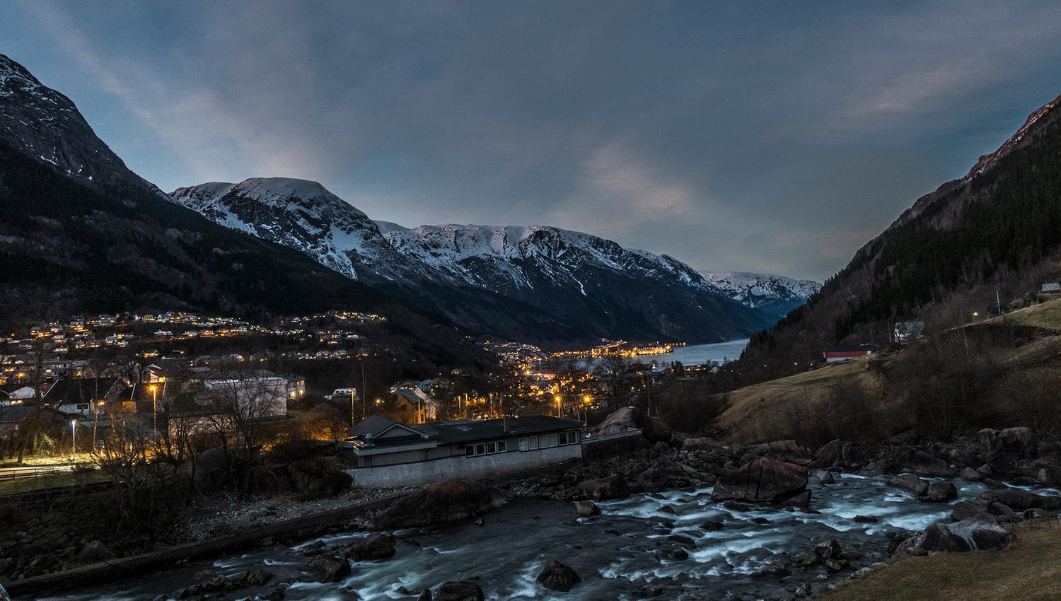 Spektakulær kveldsscene med fjord, elv og fjell opplyst av dei siste solstrålene.