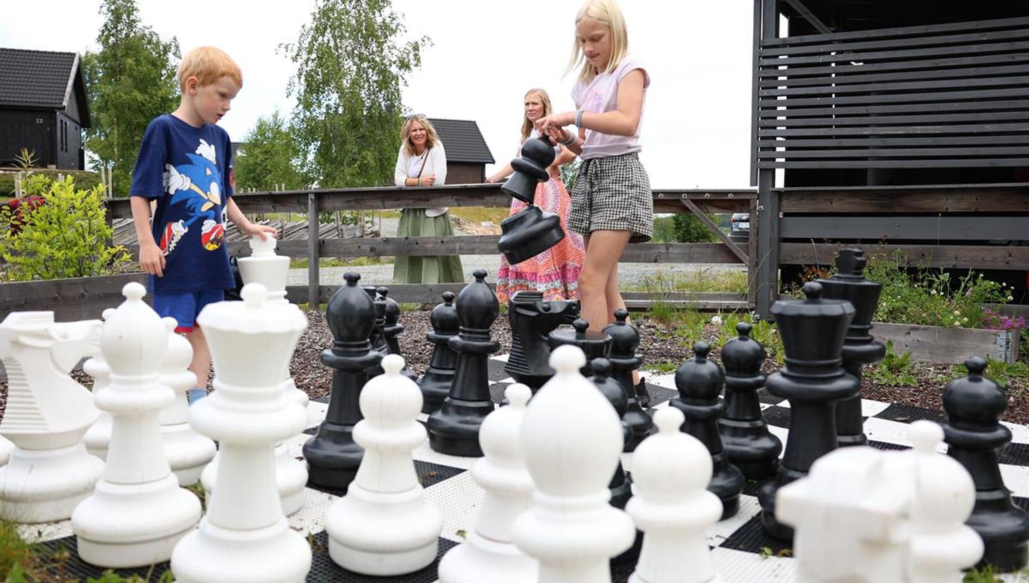 Large outdoor chess set with people moving the pieces.
