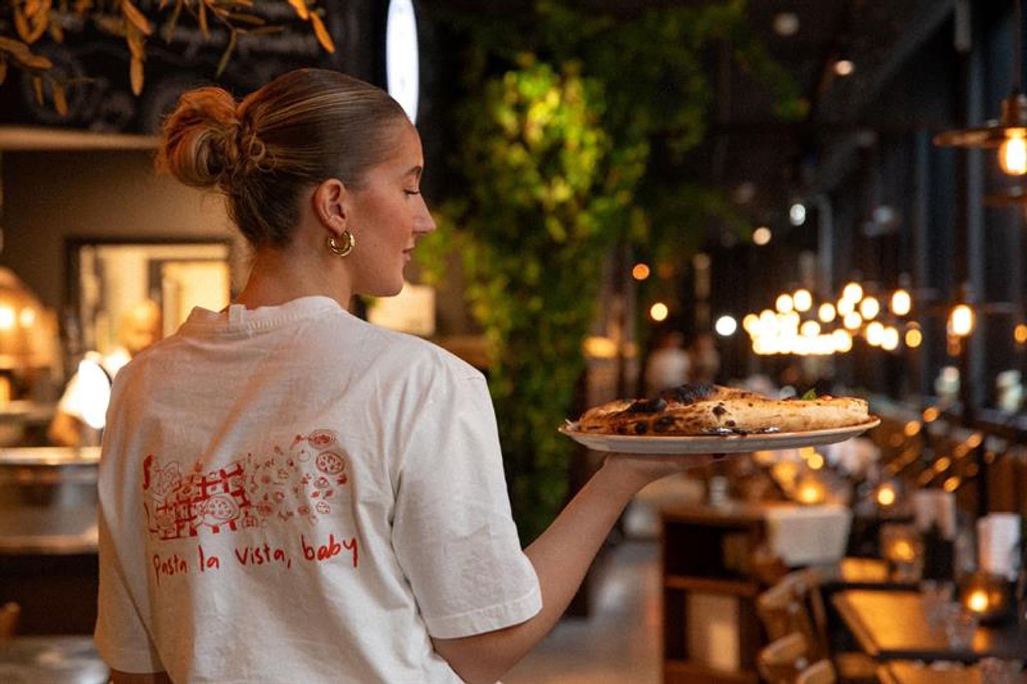 Female server carrying a plate of pizza