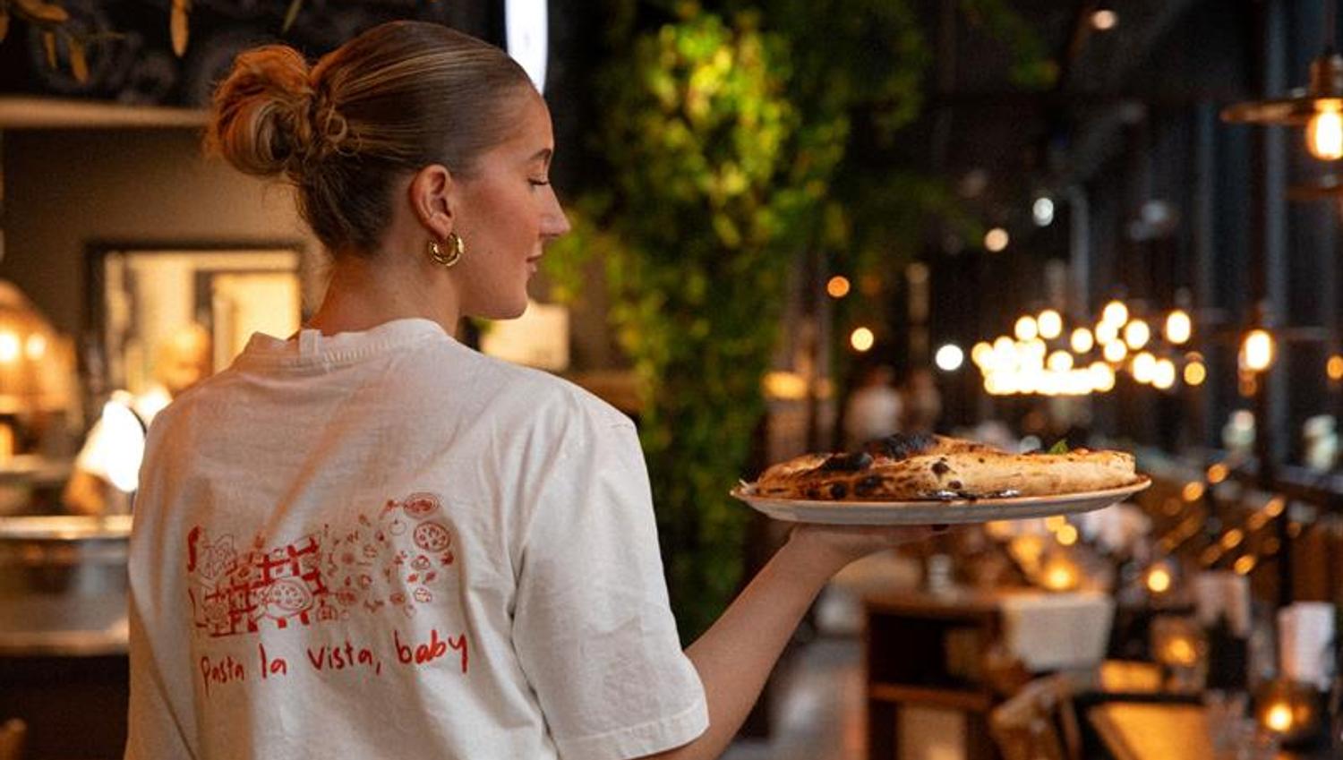 Female server carrying a plate of pizza