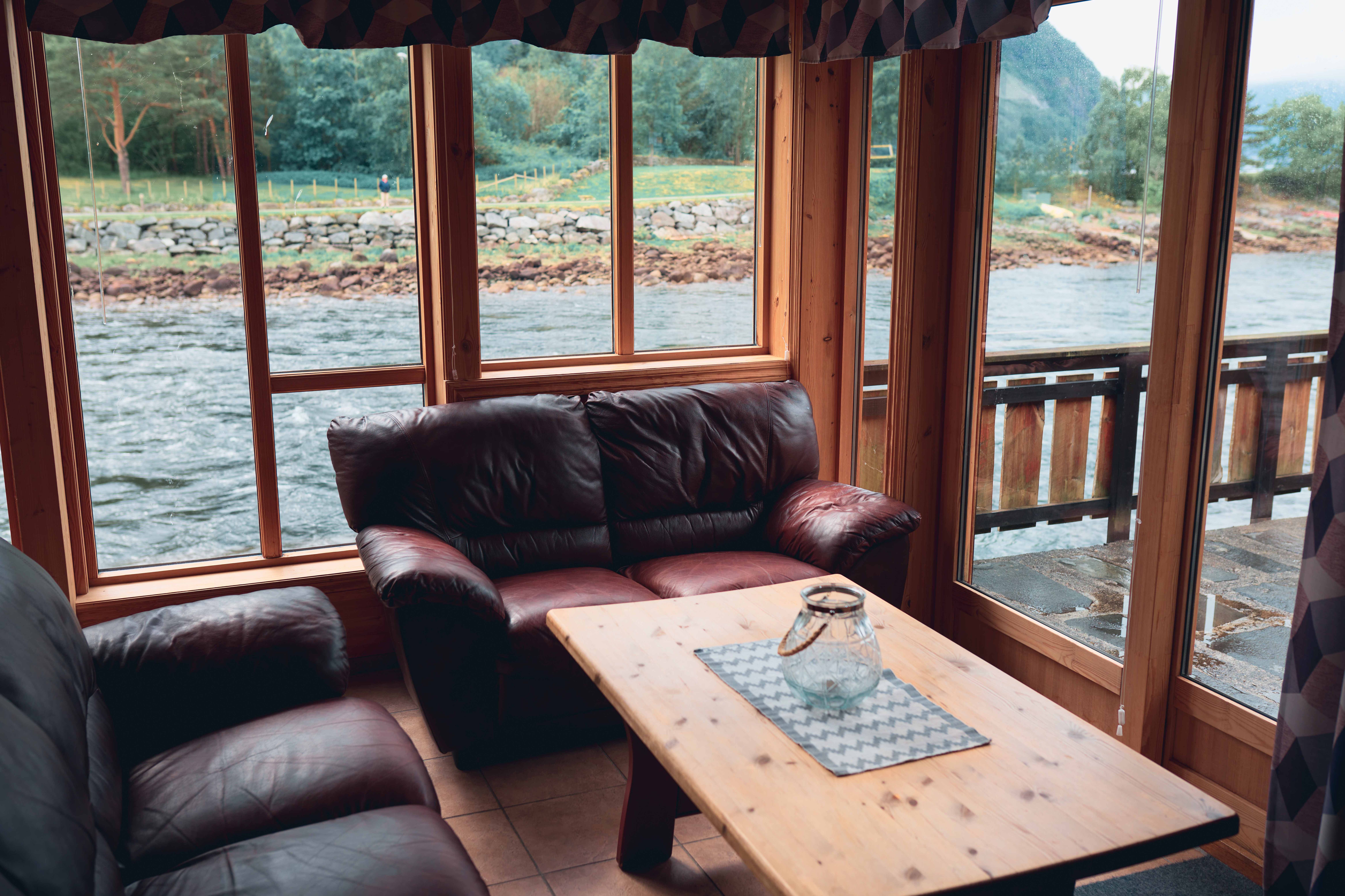 One of the riverside cabins fom the inside, with the sitting area and the river flowing by outide the window.