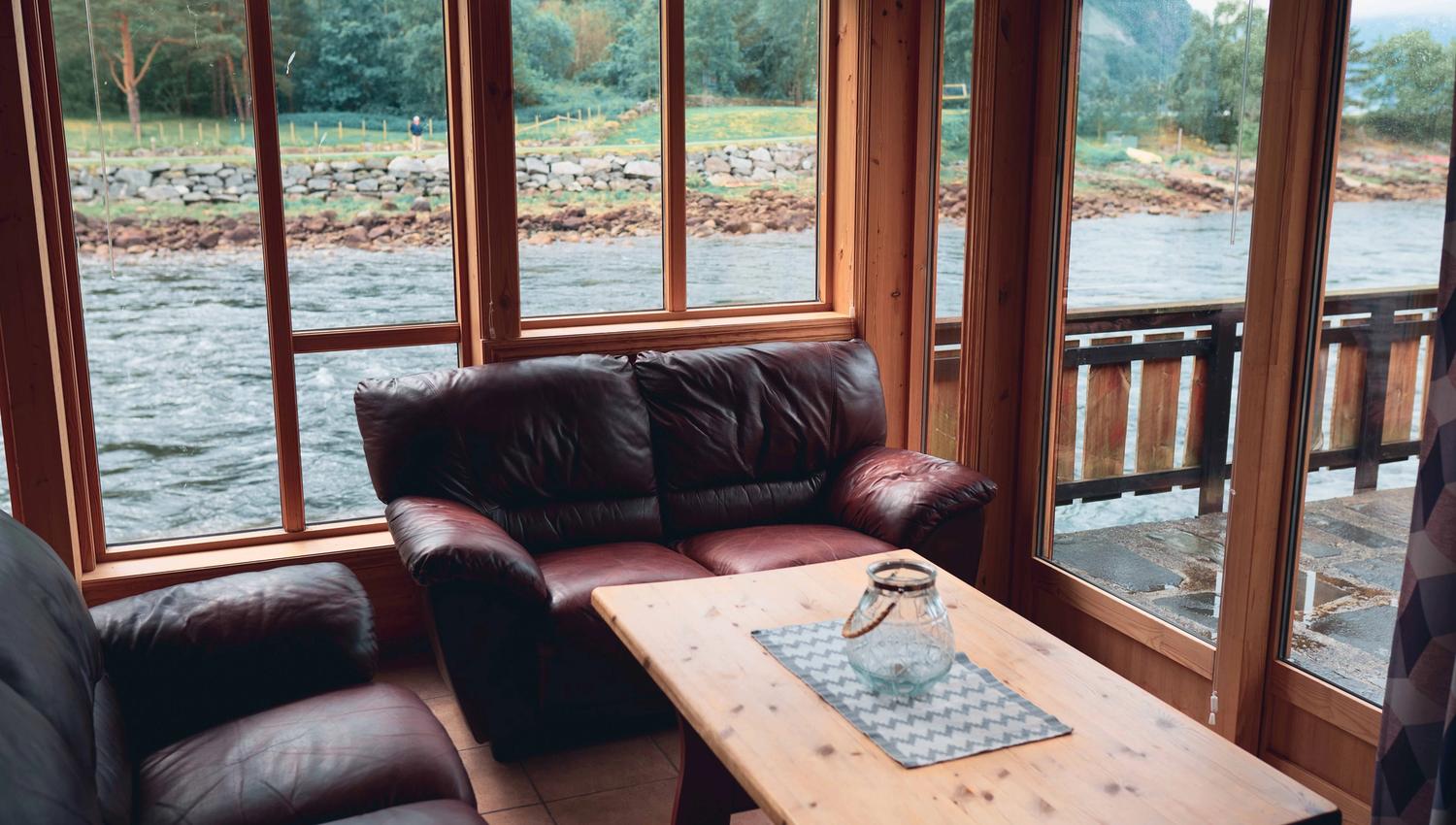 One of the riverside cabins fom the inside, with the sitting area and the river flowing by outide the window.