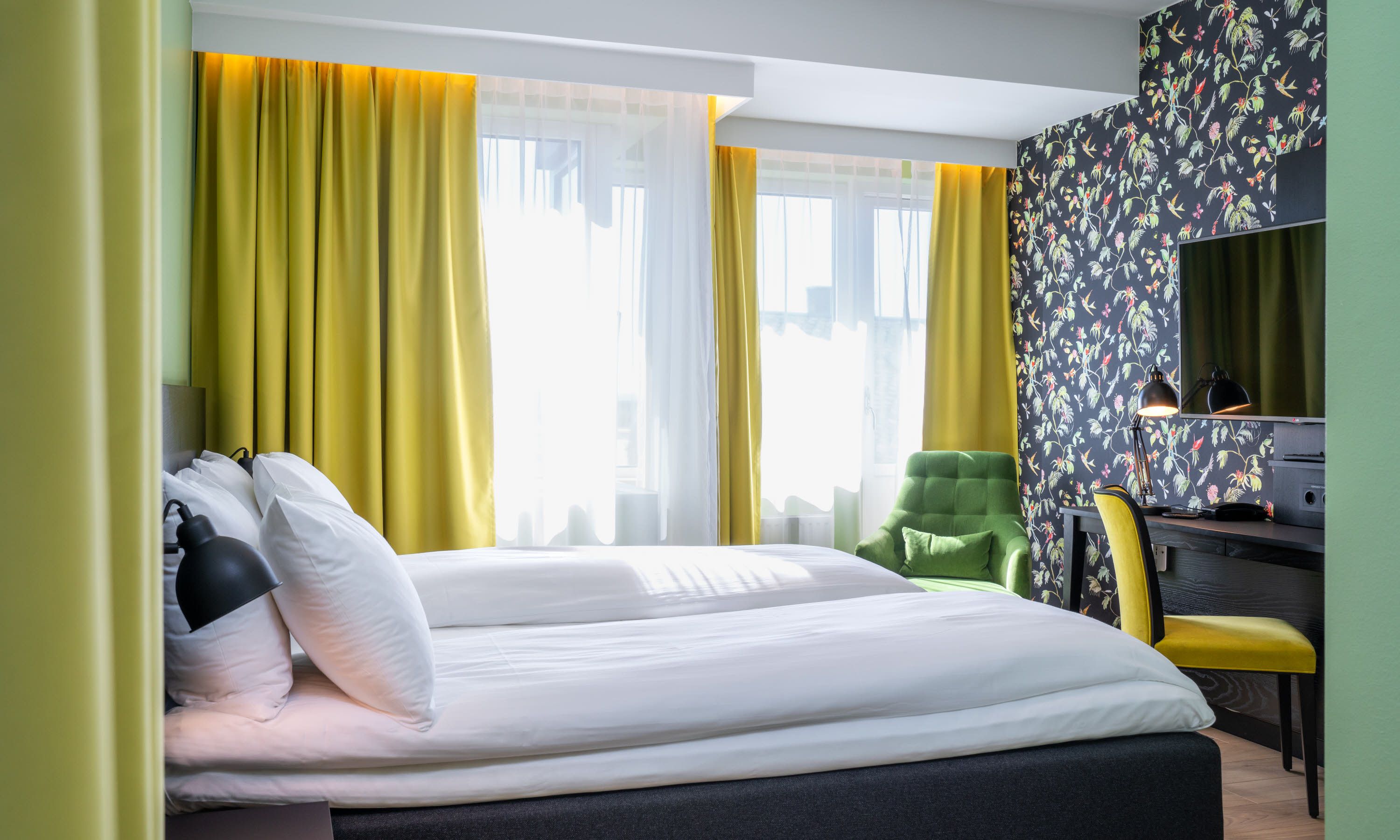 Seng og skrivebord i gult og grønt. Superior room Thon Hotel Gyldenløve. Foto