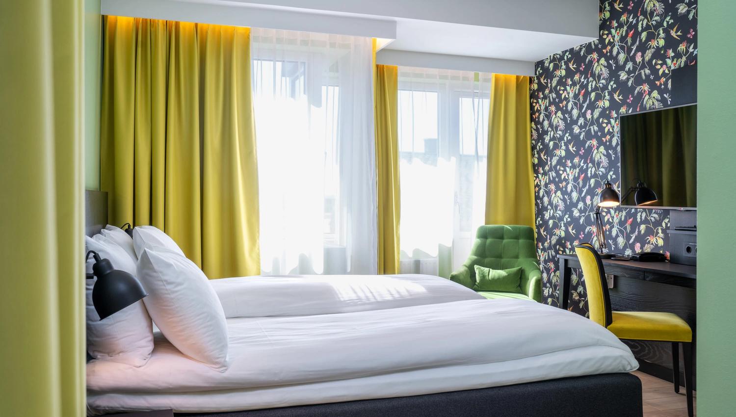 Seng og skrivebord i gult og grønt. Superior room Thon Hotel Gyldenløve. Foto