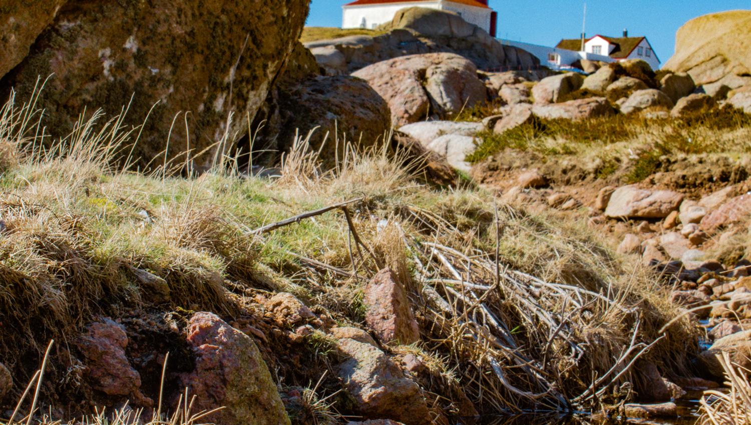 Ryvingen fyr, som speiler seg i en liten vanndam mellom fjell og steiner