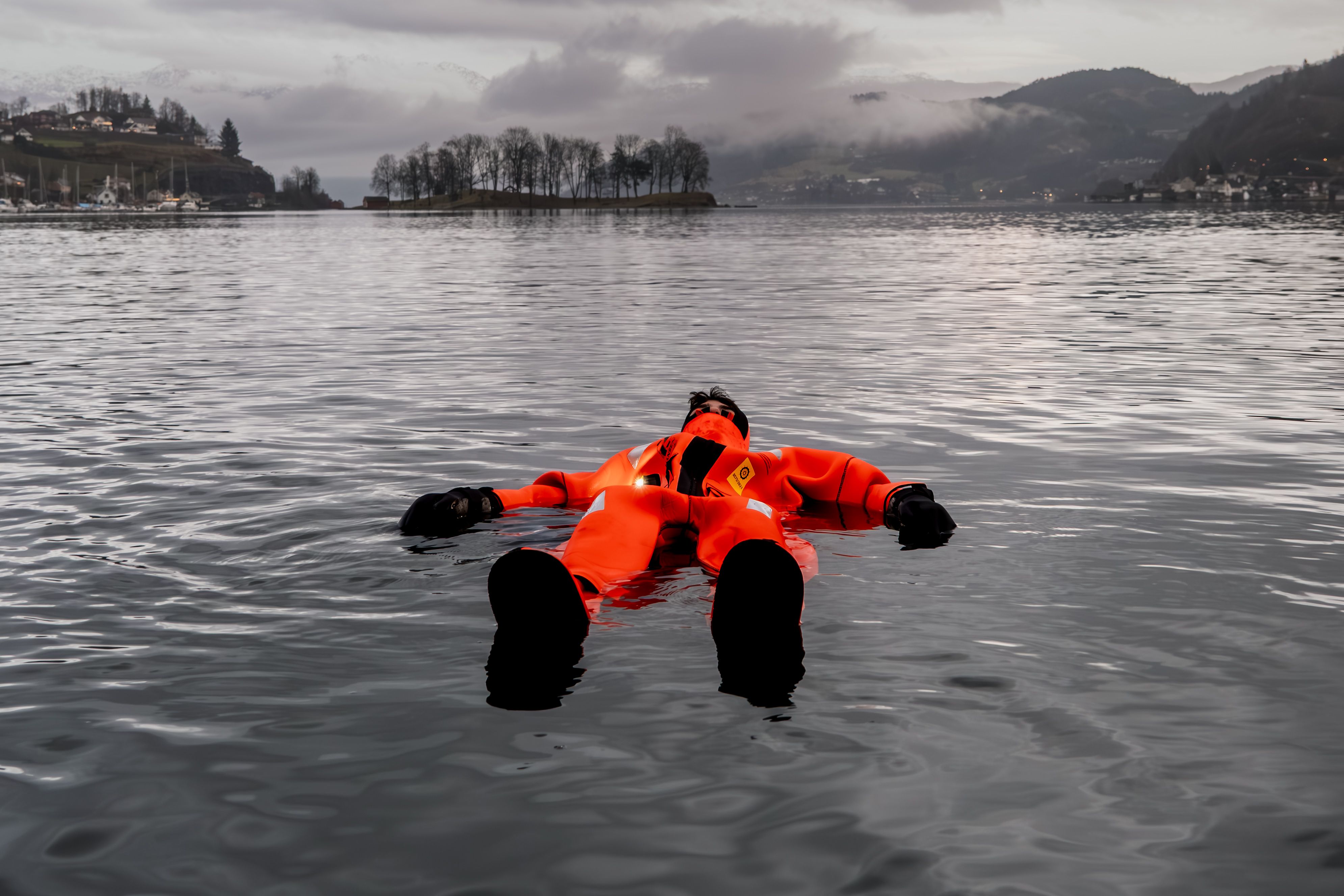 En person nyter å flyte i Hardangerfjorden utenfor Thon Hotel Sandven