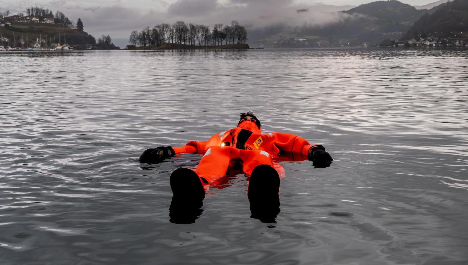 En person nyter å flyte i Hardangerfjorden utenfor Thon Hotel Sandven