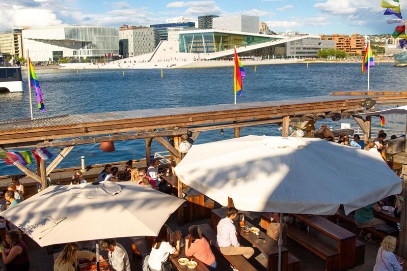 the outdoor area at SALT with guests and a view of the opera house on a sunny day
