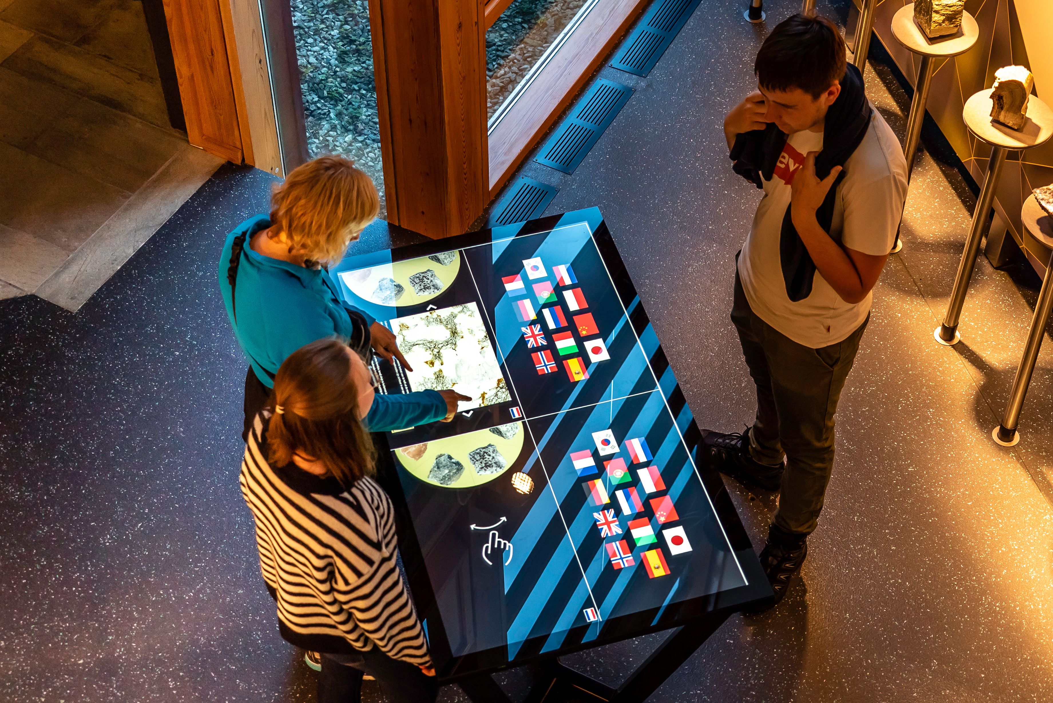 Three persons playing with a touch screen display.