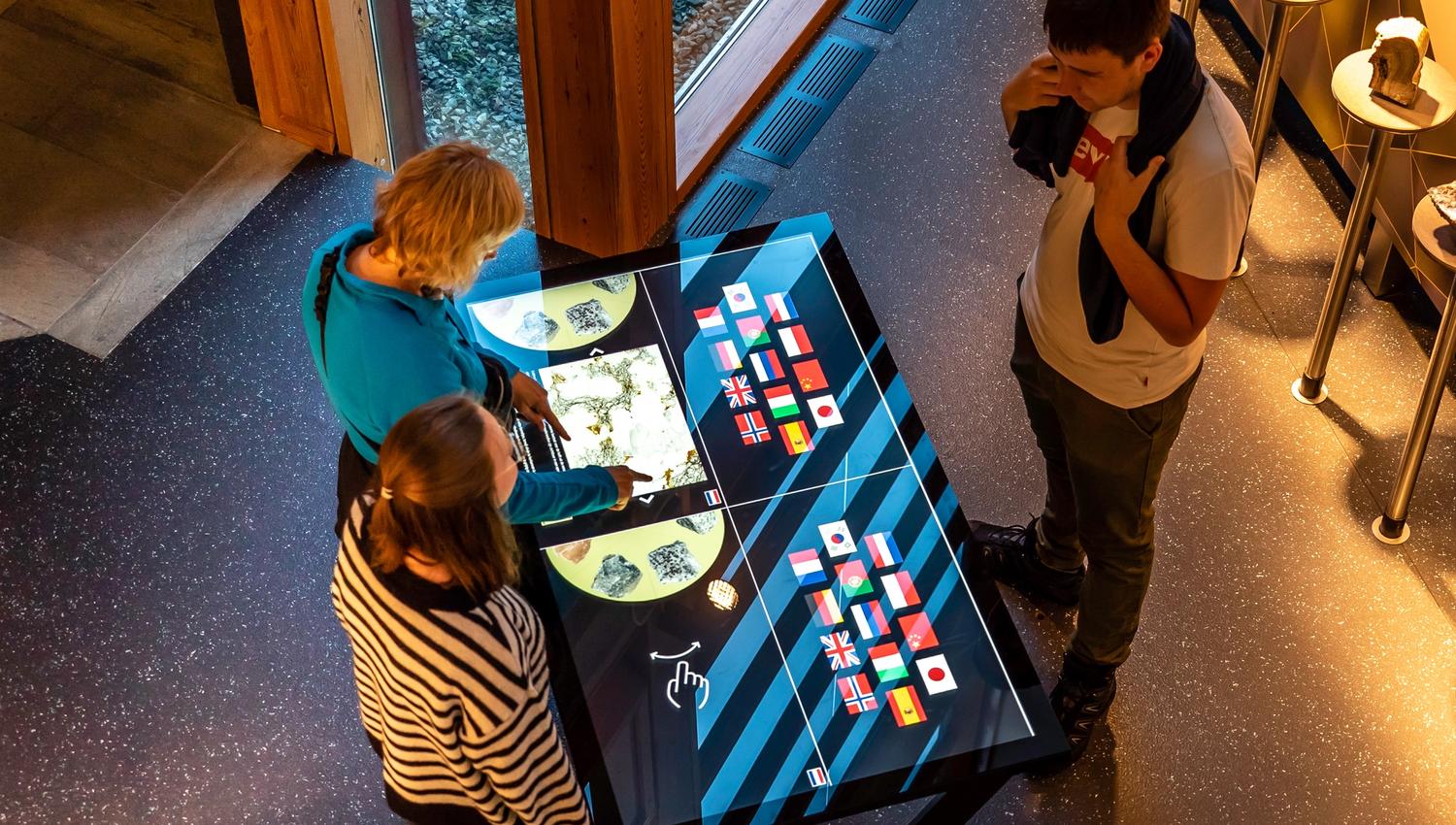 Three persons playing with a touch screen display.