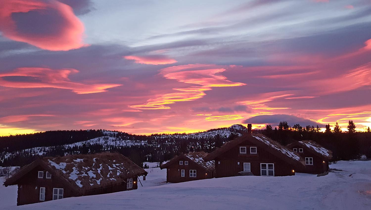 Small wooden cabins in a winter landscape in the sunset