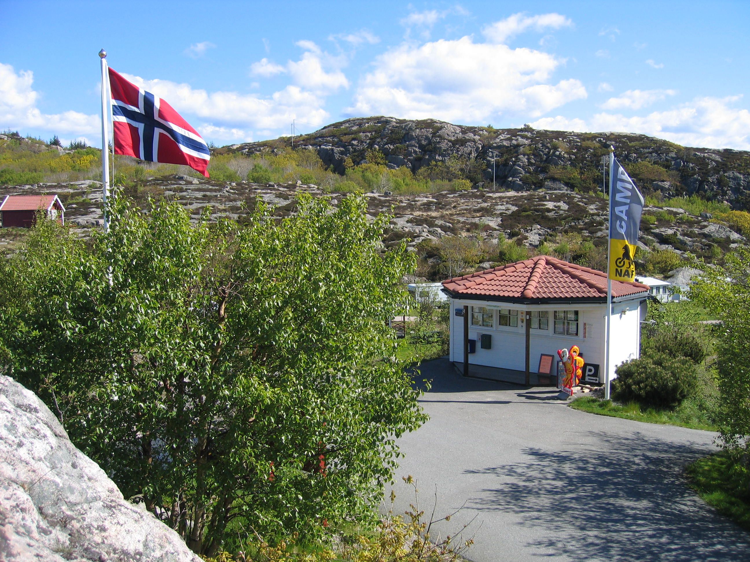 Resepsjonen og kiosken i samme hvite bygningen, norsk flagg på flaggstanga vedsiden av bygningen