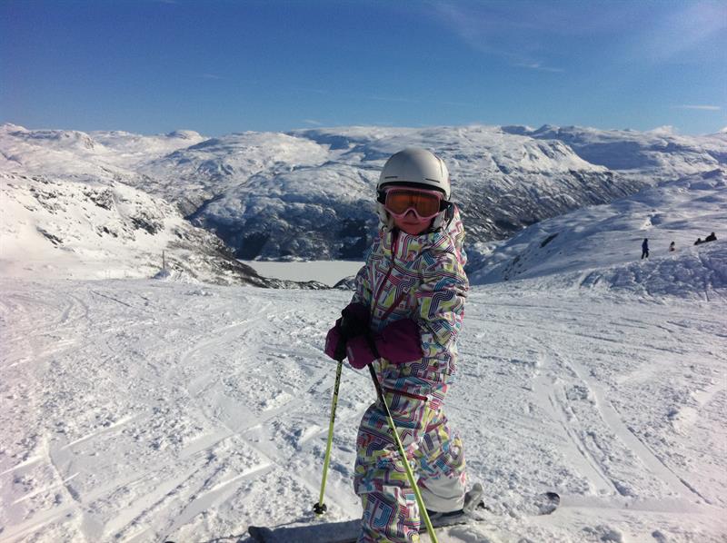 Child skiing at Røldal Ski Resort with stunning views of the mountains and fjord.