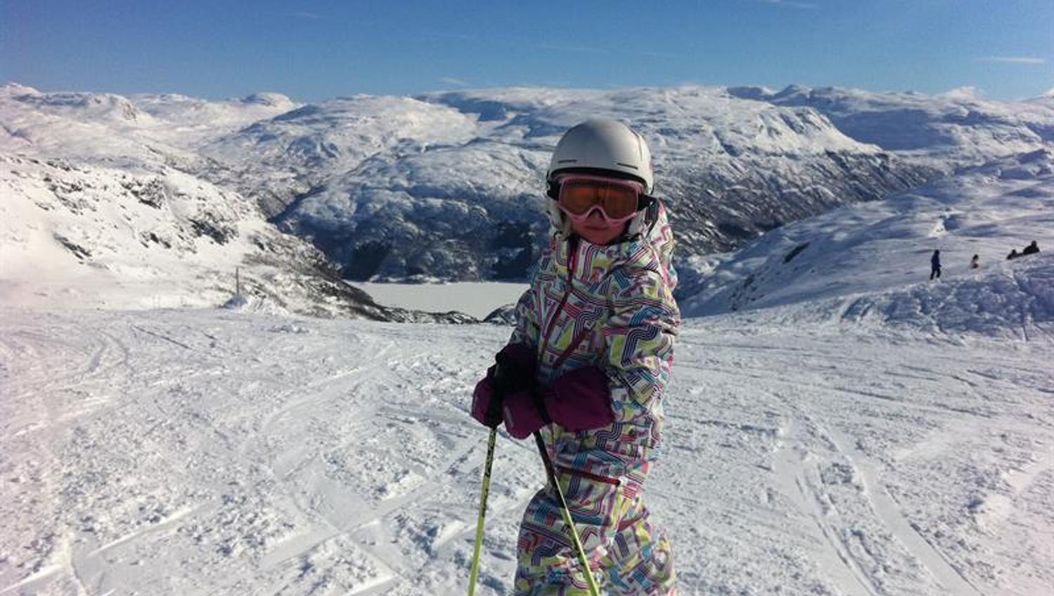 Child skiing at Røldal Ski Resort with stunning views of the mountains and fjord.