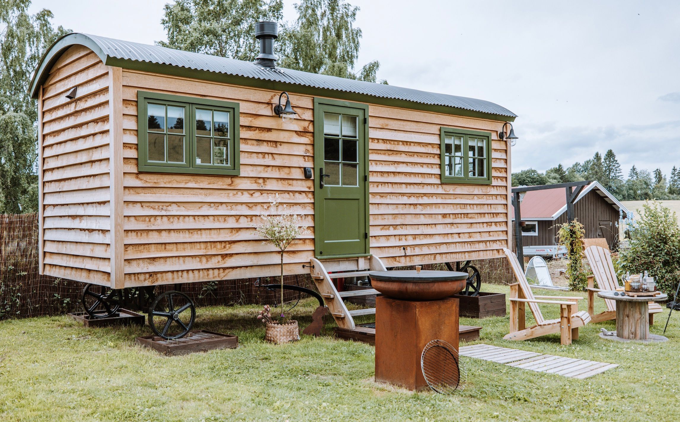 lite trehus med grønne vinduer og stoler foran