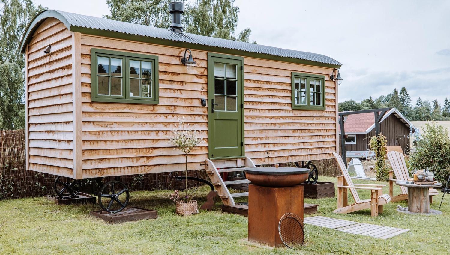 lite trehus med grønne vinduer og stoler foran