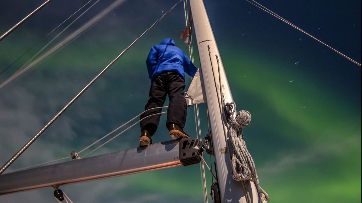 A person on a sailing boat looking at the Northern Lights