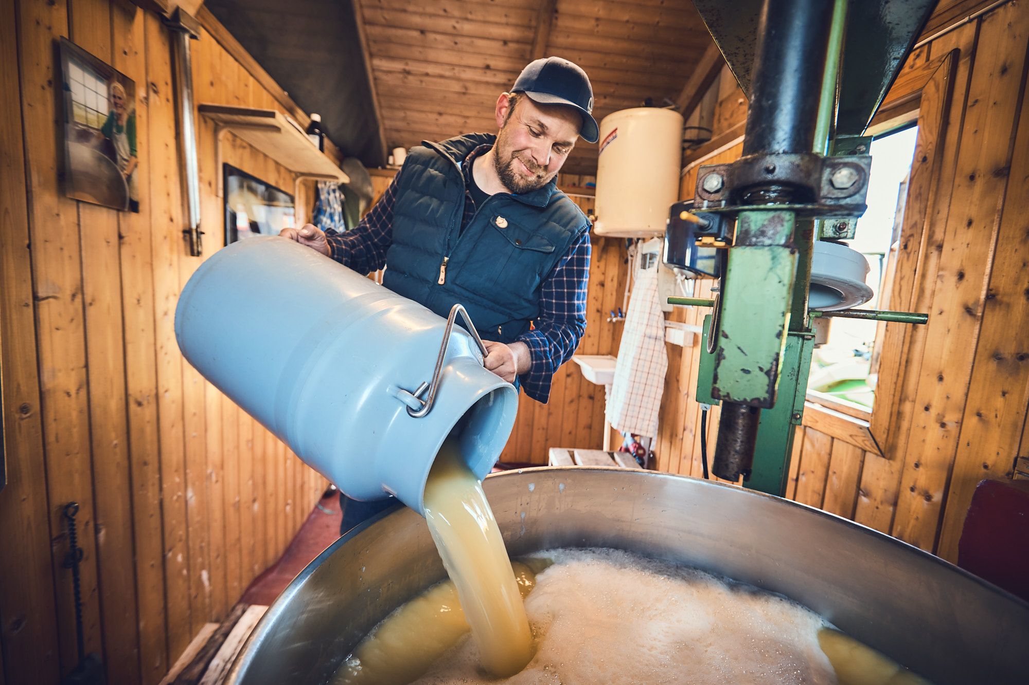 Mann som heller melk i stort kokekar.