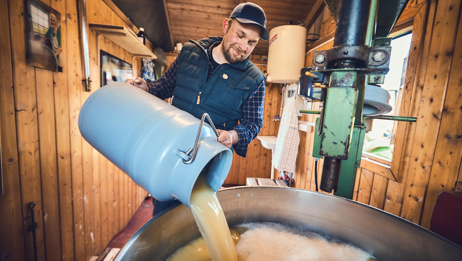 Mann som heller melk i stort kokekar.