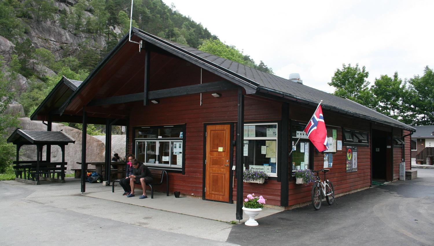 Campingresepsjon med uteområde og sitjeplassar ved fjellet.