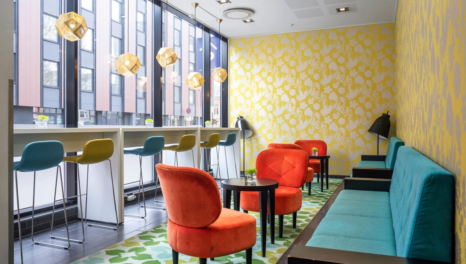 Colourful lounge with large windows, seating areas, and modern furnishings.