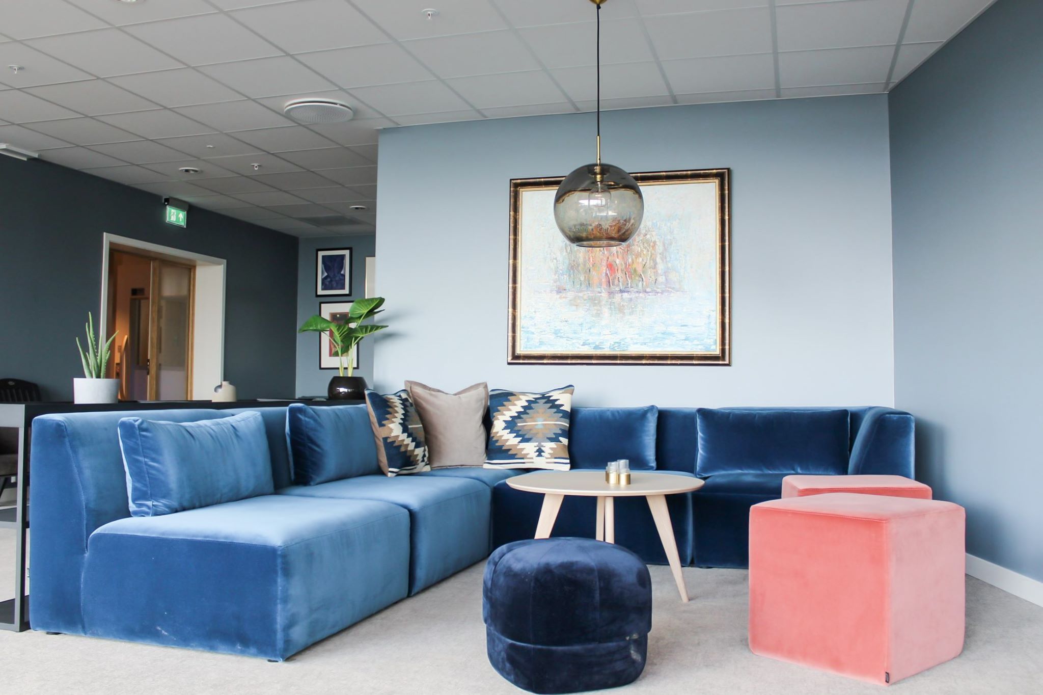 Mjuk sofa i blått med dekorative puter i eit stilfullt loungeområde.
