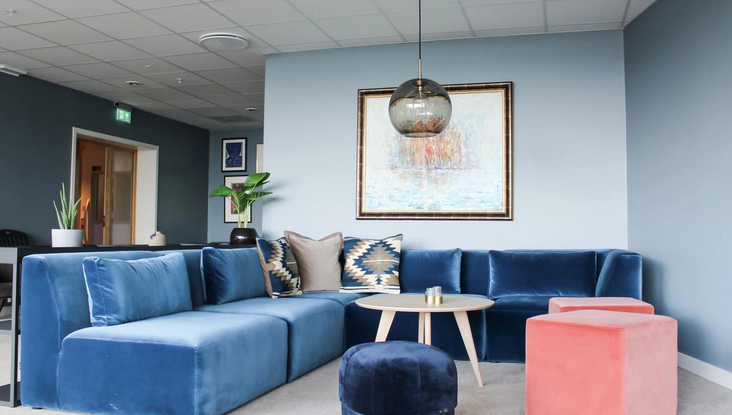 Mjuk sofa i blått med dekorative puter i eit stilfullt loungeområde.
