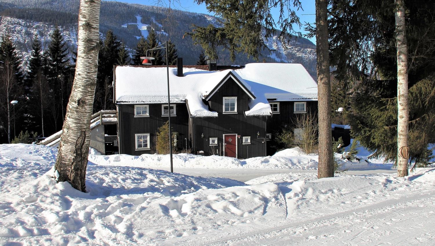 The barn is a large cabin with snow on the roof.