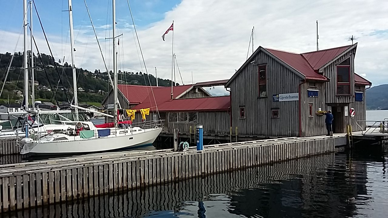 Gjestehamna i Norheimsund med båtar, trebrygger og maritime bygg med raude tak.