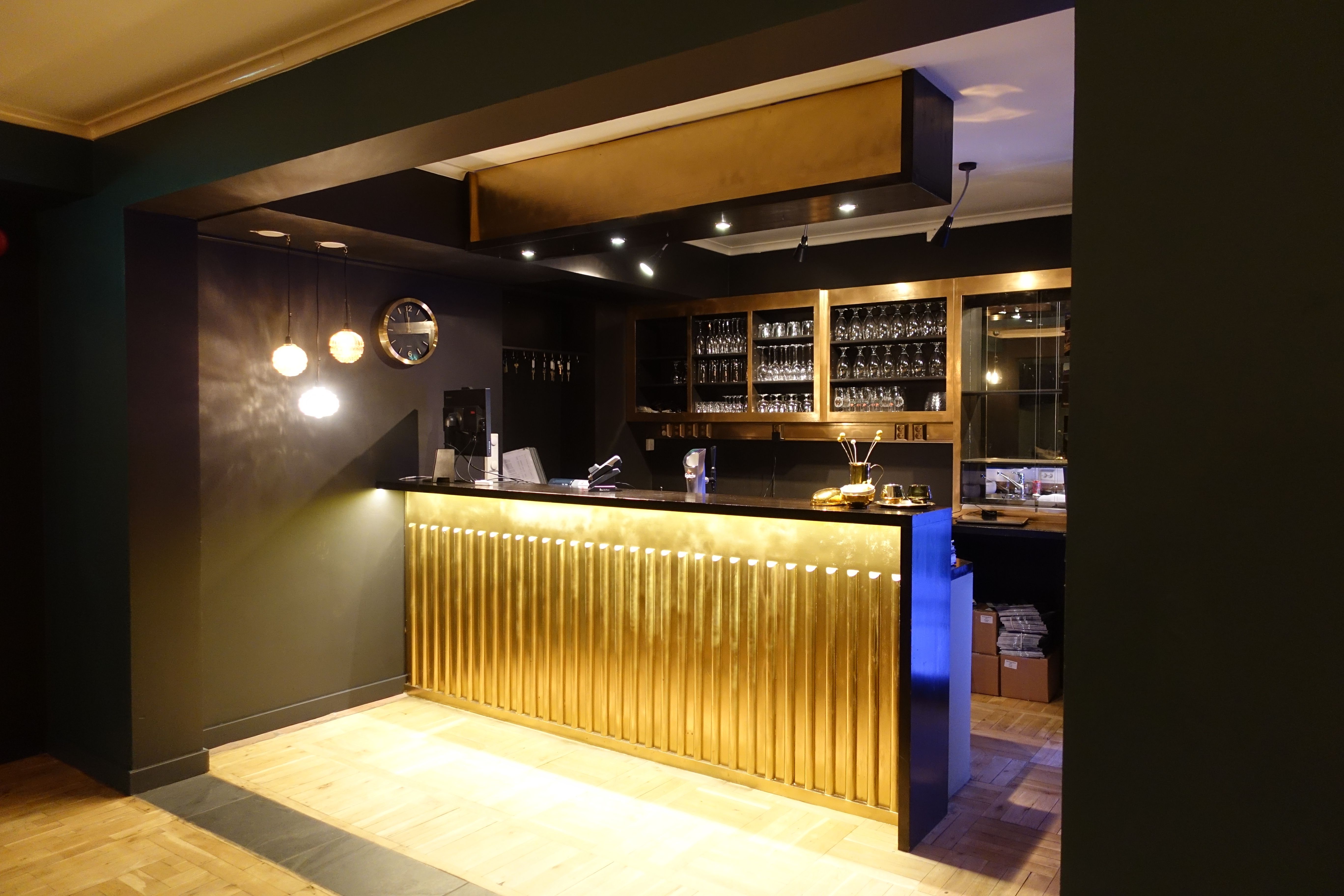 Ein moderne bar med gyldne detaljar – perfekt for ein hyggeleg kveld på Trolltunga Hotel.