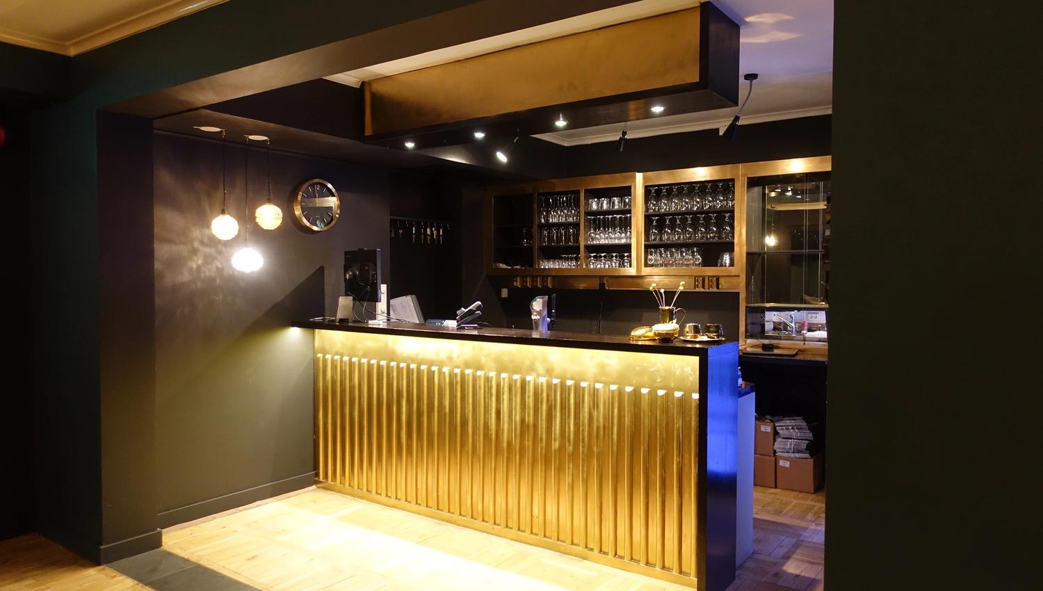Ein moderne bar med gyldne detaljar – perfekt for ein hyggeleg kveld på Trolltunga Hotel.
