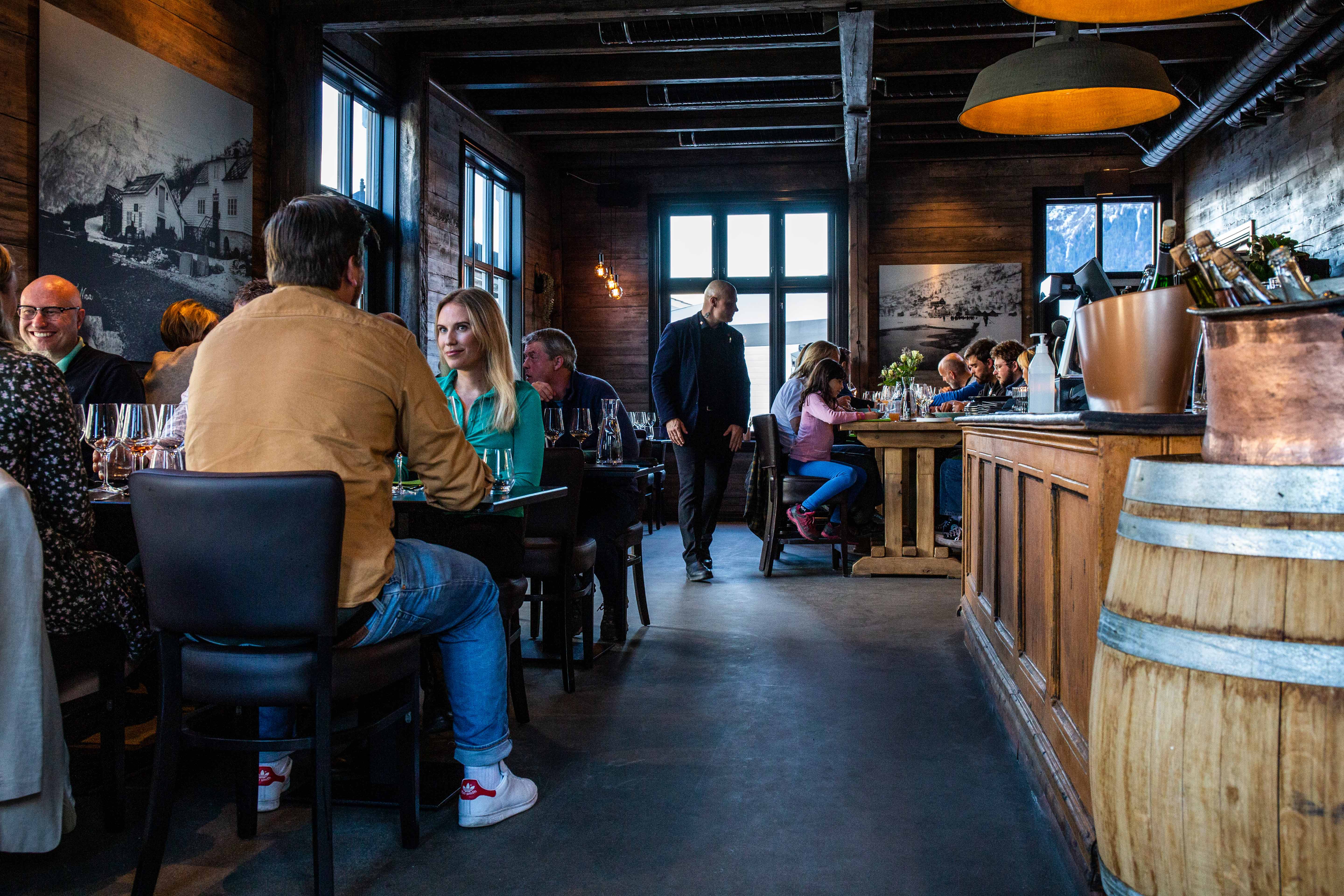 Cozy atmosphere inside Siderhuset Ola K, where guests enjoy local delicacies in a historic setting.