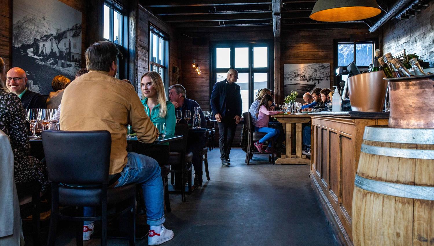 Cozy atmosphere inside Siderhuset Ola K, where guests enjoy local delicacies in a historic setting.