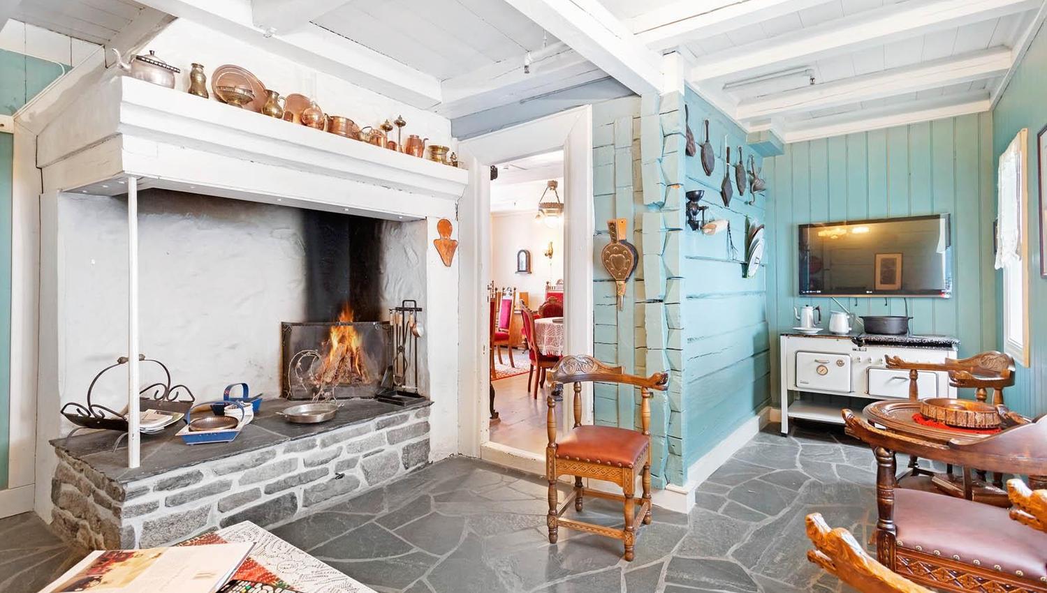 Cozy living room with open fireplace and traditional decor at Jaunsen Guesthouse in Hardanger, Norway.