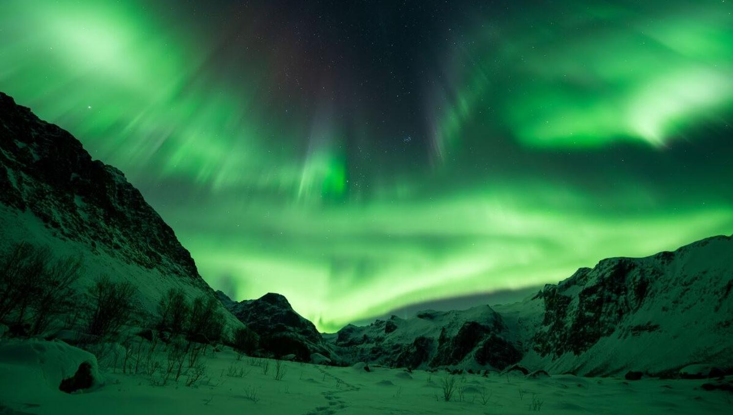 Nordlyset skinner ut siden av et fjell