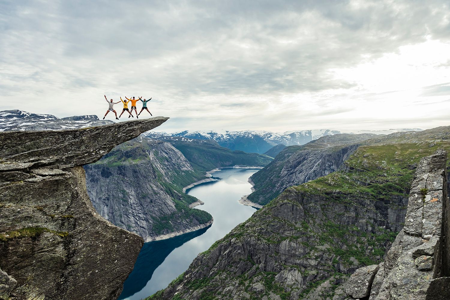 En gruppe mennesker står på fjellformasjonen Trolltunga med utsikt til Ringedalsvatnet.