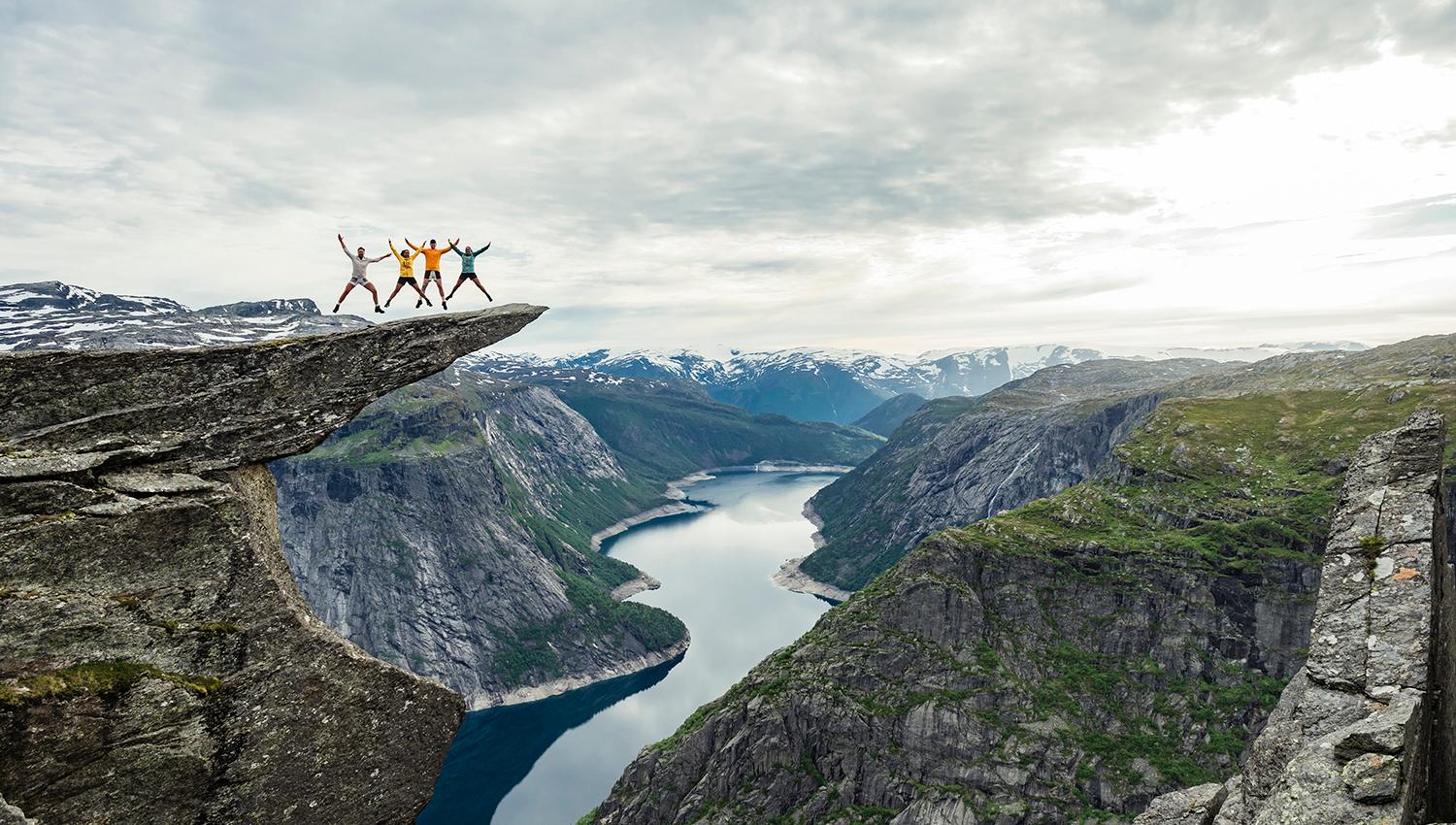 En gruppe mennesker står på fjellformasjonen Trolltunga med utsikt til Ringedalsvatnet.