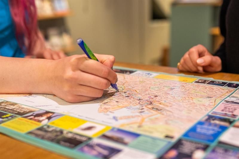 Nærbilde av en ansatts hånd som holder en penn og krysser av på et kart