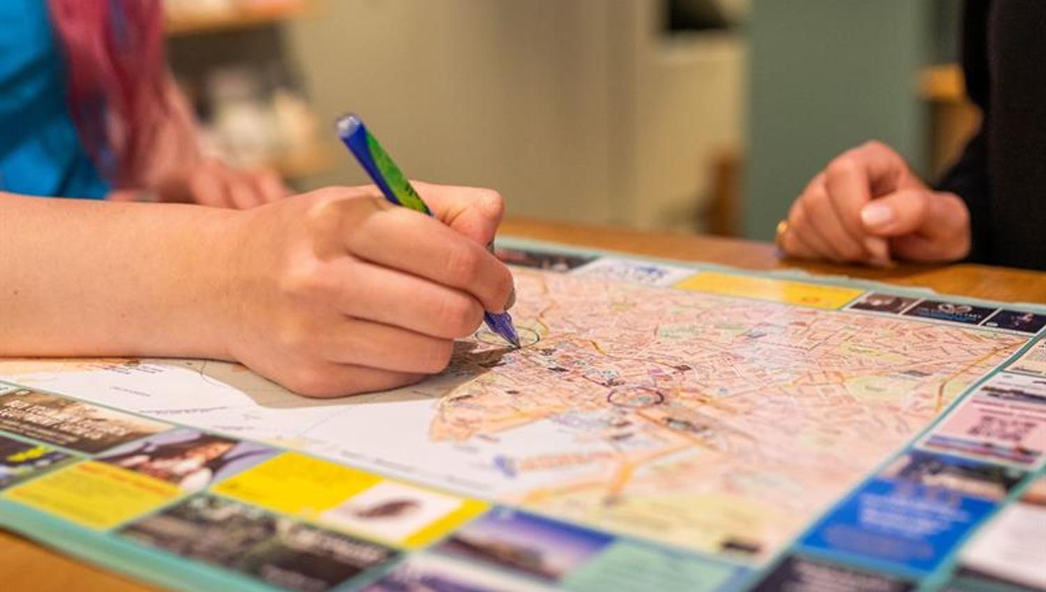 Nærbilde av en ansatts hånd som holder en penn og krysser av på et kart