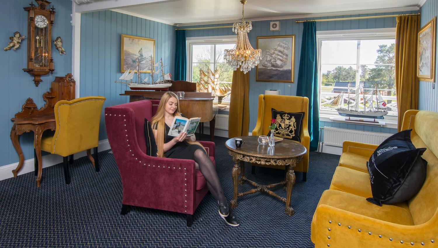 hotellgjest som sitter og leser en bok i penstua på hotellet