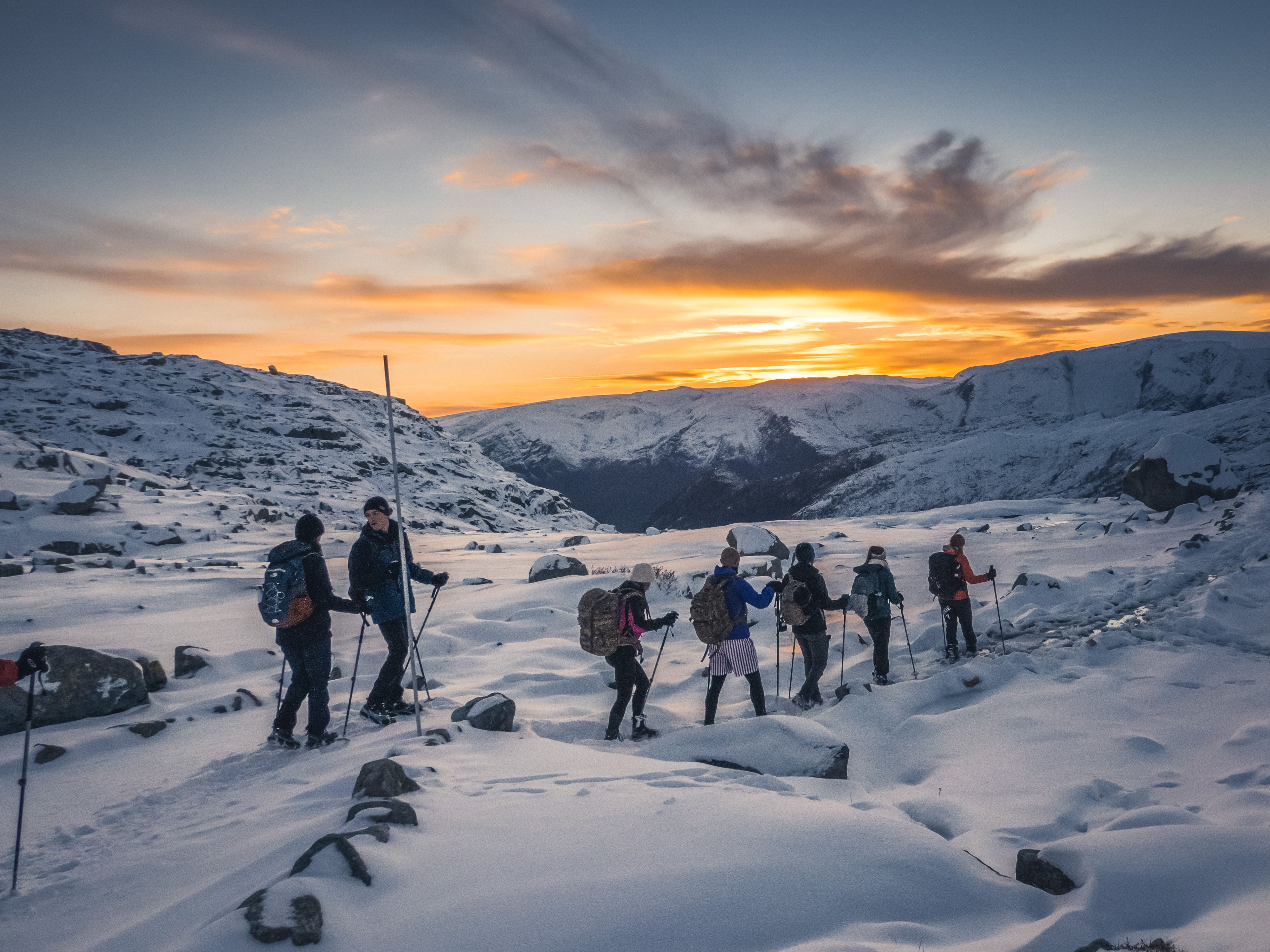 Group on a winter hike at sunset on the trail to Trolltunga.