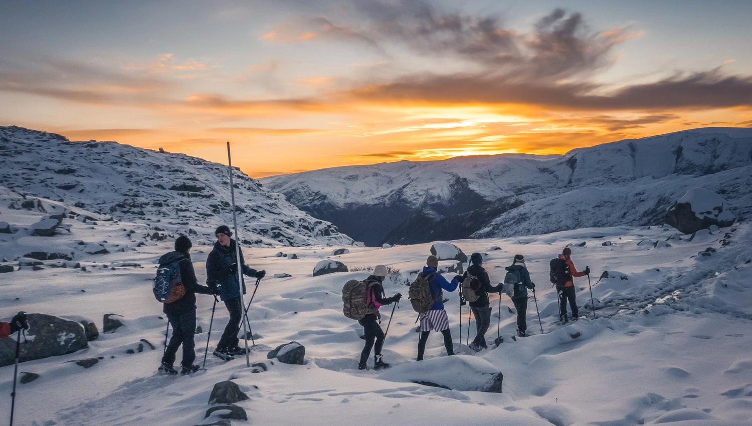 Group on a winter hike at sunset on the trail to Trolltunga.