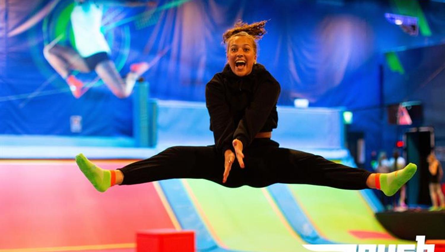 Jente som tar splitthopp på trampoline.
