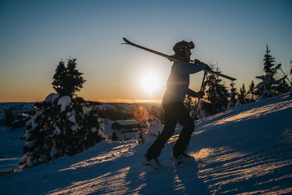 mann går opp en bakke med ski på skuldra på Lifjell skisenter i Bø