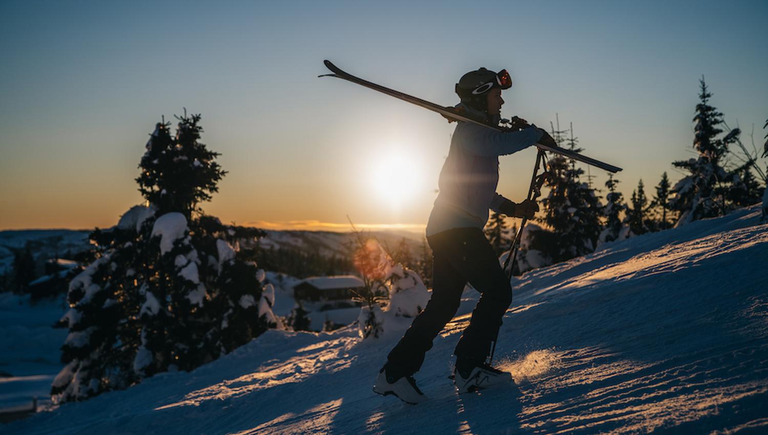 mann går opp en bakke med ski på skuldra på Lifjell skisenter i Bø
